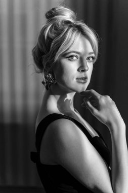 Siyah bluzlu güzel bir sarışının stüdyo portresini kapat ve kameraya bak..