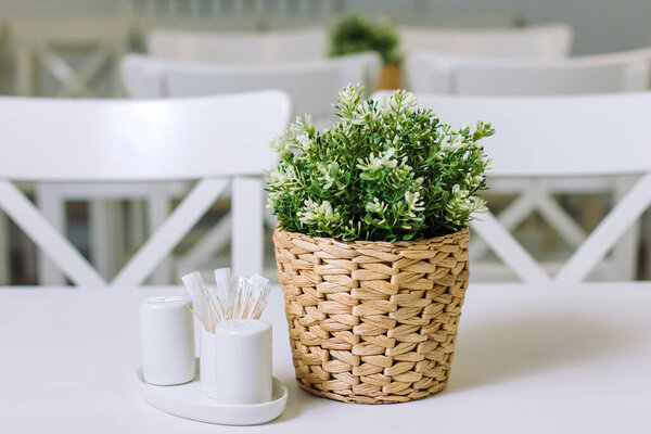 A pot of plastic plants, on a table in a wicker pot.