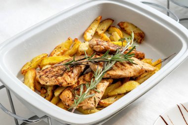 Kızarmış patatesli tavuk, beyaz tabakta hazır. Biberiyeyle süslenmiş..