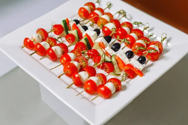 Cheese and olive canapes with tomato and cucumber. Also a quail egg. — Stock Photo, Image