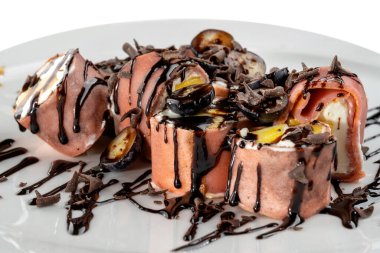 İçinde çeşitli meyveli ve kremalı peynir olan tatlı rulo. Üzerine rendelenmiş çikolata ve çikolata sosu serpilmiş.