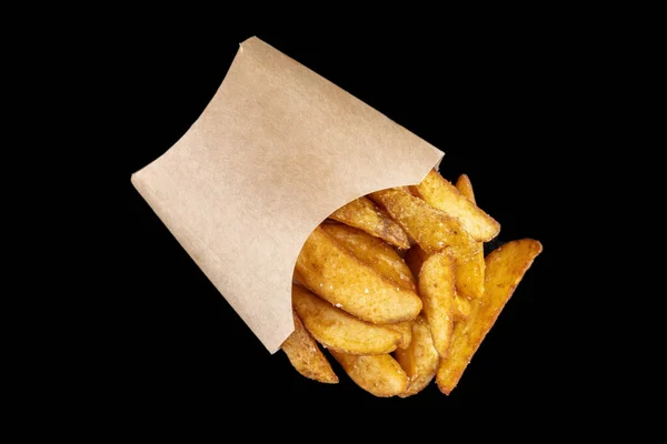 Des quartiers de pommes de terre frites renversés dans un sac en papier. — Photo