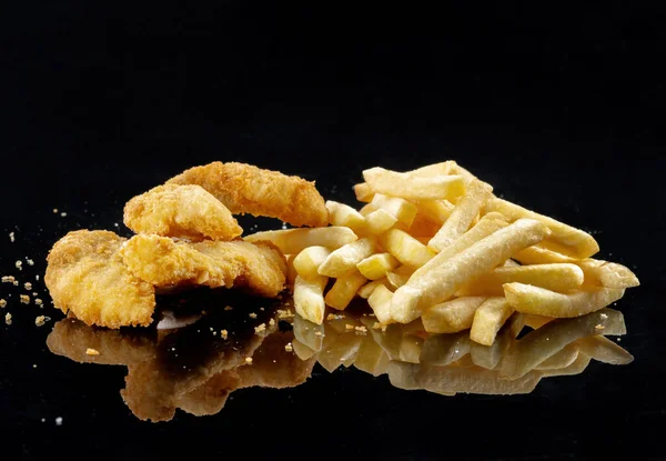 Kızarmış tavuk ve kızarmış balık parçalarının resmi. En iyi yemektir. Siyah bir aynaya serilmiş.