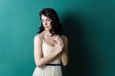 Zarif bir bayan portresi. Stüdyonun yeşil arka planında incilerin poz vermesi. Şehvetli görünüm aşağı doğru