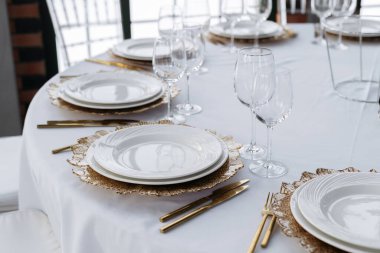 Beautiful served table, golden coasters, golden cutlery. Wedding event, luxury catering.