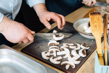 Şef tahta üzerinde mantar kesiyor. Gerçek mutfak, stüdyo değil..