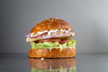 Gri metal bir masada soğanlı ve mayonezli hamburger..