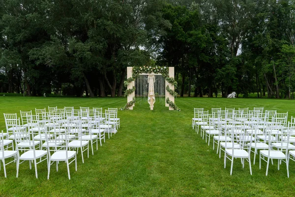 Свадьба в парке на открытом воздухе. Красивое платье висит на свадебной арке. Вид спереди. — стоковое фото