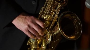 Müzisyen saksafon çalıyor. Enstrümanın tuşlarına basarak parmakları yakın çekim