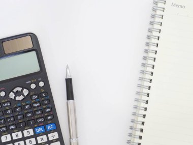 Beyaz arkaplan resmi üzerine bilimsel hesap makinesi kalem ve not defteri.