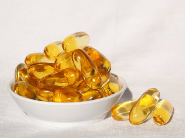 Omega-3 karaciğer yağı beyaz bir kabın içinde ve beyaz bir arkaplan resmiyle.