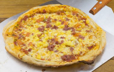Pastırma, peynir, domates ve ananas metal pizza spattula üzerinde pizza