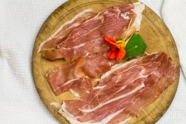 rustik ahşap tahta üzerinde caper yaprağı ve çiçekli prosciutto dilimleri - fotokopi alanı ile üstten görüntü