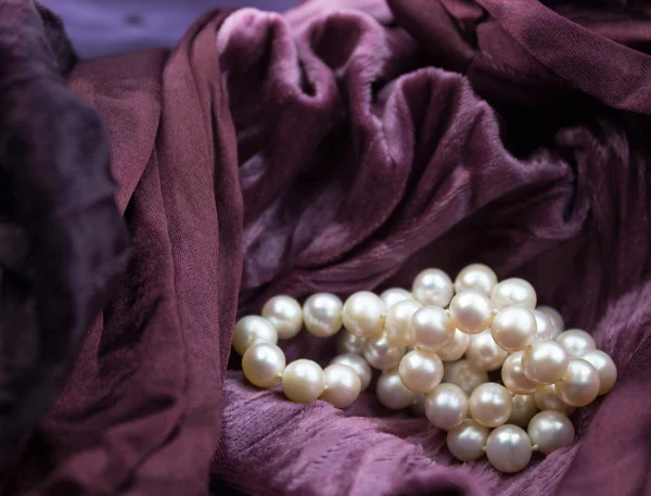 Pink cultured pearls on burgundy velvet crumpled dress backgroun — Stock Photo, Image