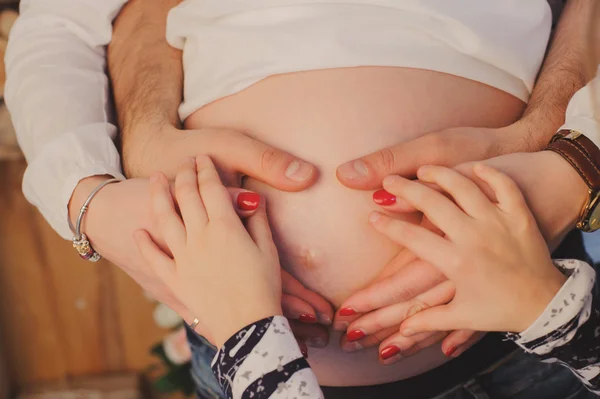 Donna incinta abbraccia la pancia con marito e figlio . — Foto Stock