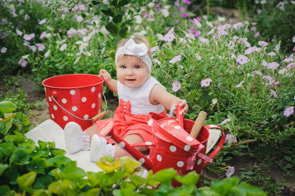 Gülümseyen bebek yeşil çim ve çiçek dott ile oturuyor