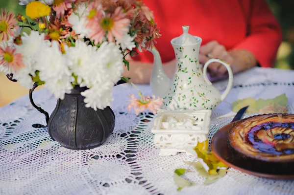 Appetitliche Torte mit Herbstblumen und leckerem Tee auf dem Tisch. — Stockfoto