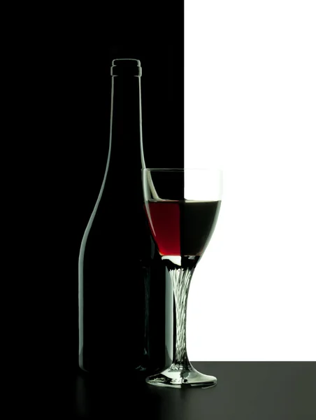 Μπουκάλι κόκκινο κρασί με το ποτήρι πάνω σε μαύρο φόντο — Φωτογραφία Αρχείου