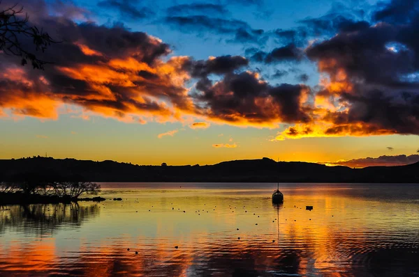 Pôr-do-sol colorido com um barco em Lake Taupo, Nova Zelândia — Fotografia de Stock