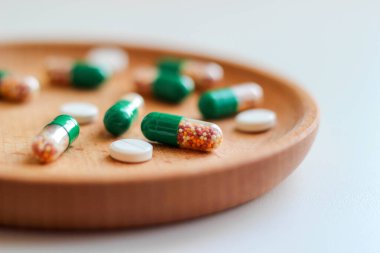 Bağırsak çözünür kapsüller ve tahta tabakta vitamin içeren haplar. Sağlık hizmeti, ilaç. Yaklaş, makro fotoğraf.