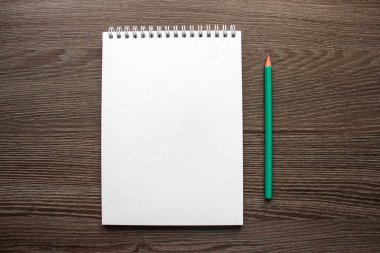 Masanın üzerinde boş bir not defteri sayfası, bir kalemin yanında.