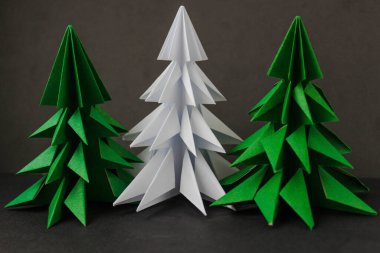 İki origami yeşil noel ağacı ve siyah arka planda beyaz olan..