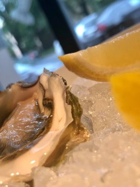 Restoranda buzlu ve limonlu beyaz tabakta istiridye.