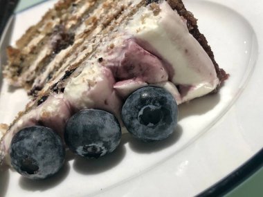 Büyük mavi böğürtlenli sünger pastası beyaz bir tabakta, yakın plan.