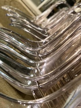 Metal çerçeve üzerinde şeffaf plastikten yapılmış pek çok sandalye duvar boyunca ayakta duruyor, alışılmadık bir açı, yan görüş.