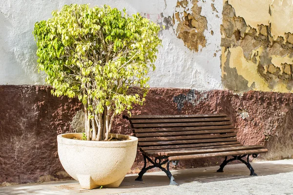 Um banco de madeira velho contra uma parede weathered em Spain . — Fotografia de Stock