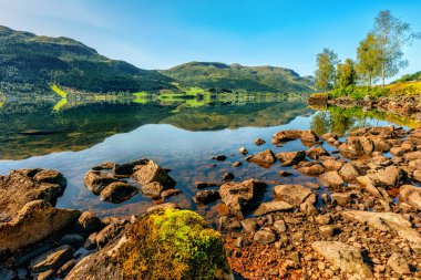 Norveç 'in durgun sularındaki yansımalar kristal berrak gölün dibi kayalık, Norveç.