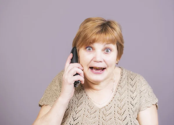 Very emotional golden teeth woman with the telephone handset on a gray background — Stockfoto