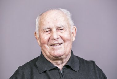 Yaşlı adam gri arka plan üzerinde gülümseyen.