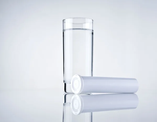 Glas water en lege geneeskunde container — Stockfoto