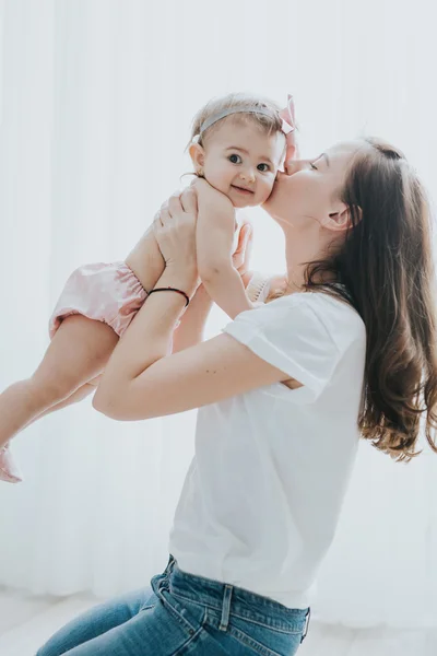 Bela mãe retrato brincando com sua menina bonito em um quarto branco na parte da manhã — Fotografia de Stock