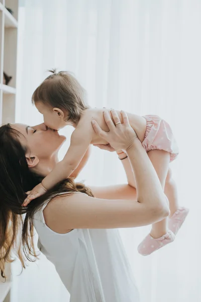Bela mãe retrato brincando com sua menina bonito em um quarto branco na parte da manhã — Fotografia de Stock