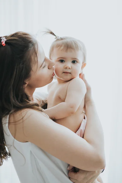 Portret matki pięknej gry z jej cute dziewczynka w białym pokoju w godzinach porannych — Zdjęcie stockowe