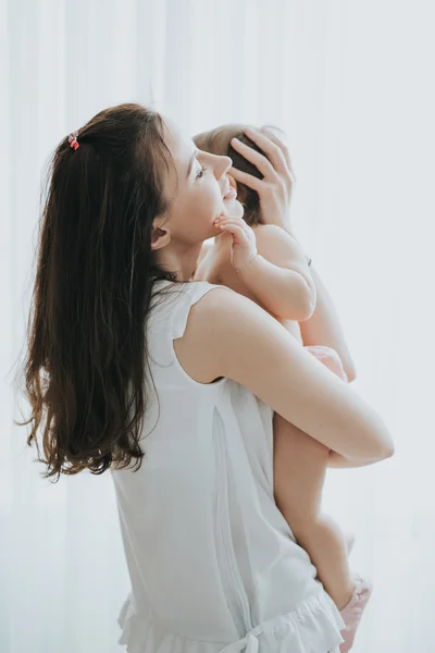 Bela mãe retrato brincando com sua menina bonito em um quarto branco na parte da manhã — Fotografia de Stock