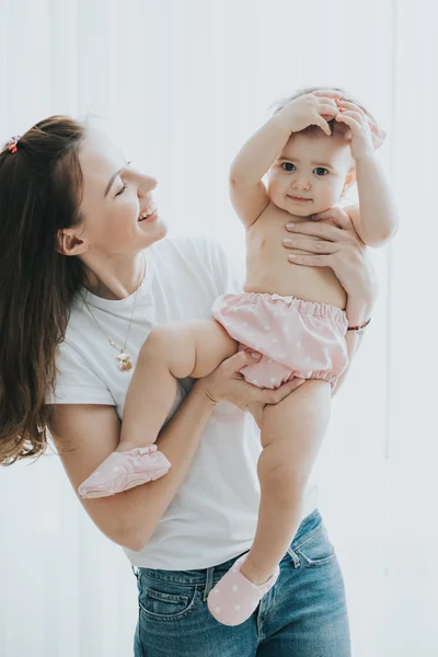 Portret matki pięknej gry z jej cute dziewczynka w białym pokoju w godzinach porannych — Zdjęcie stockowe