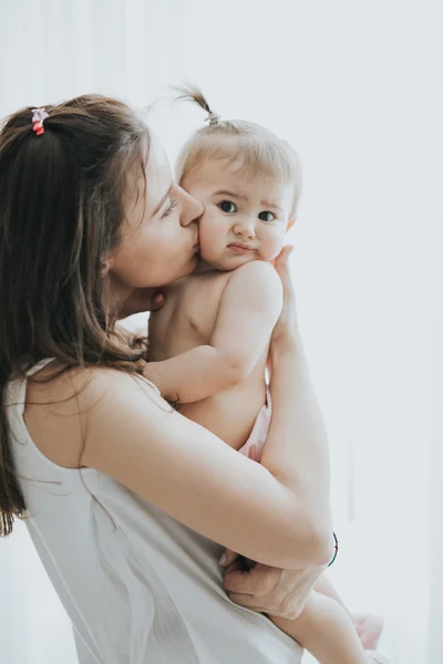Bela mãe retrato brincando com sua menina bonito em um quarto branco na parte da manhã — Fotografia de Stock