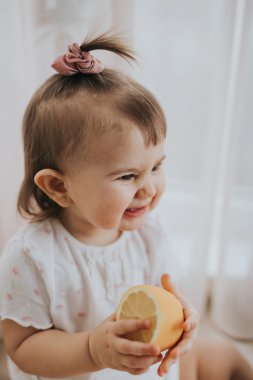 Sevimli küçük bebek kız mutfakta masada narenciye vitamin tam yiyor ve komik sevimli yüz yapıyor