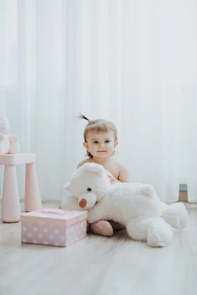 Милая девочка, играющая утром в белой комнате с игрушками — стоковое фото