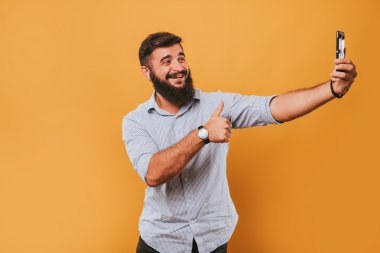 sarı stüdyo arka planda izole yakışıklı gülümseyen adam portresi kameraya poz ve komik yüzler selfie yapma