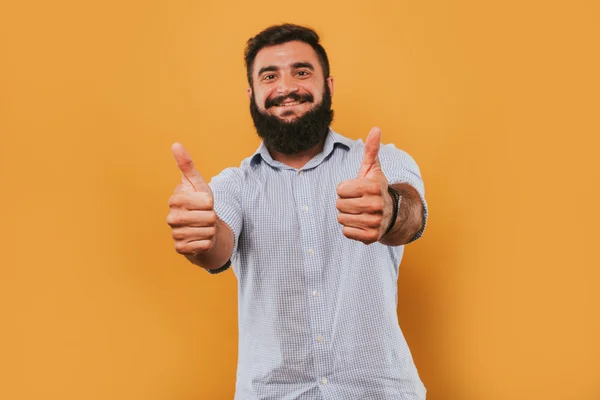 Retrato de belo homem sorridente isolado no estúdio amarelo posando para a câmera e fazendo caras engraçadas dar gostos — Fotografia de Stock