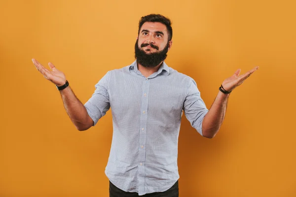 Portret van knappe lachende man geïsoleerd op gele studio achtergrond poseren voor de camera en het maken van grappige gezichten, vergelijken met handen — Stockfoto