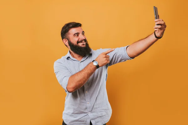 sarı stüdyo arka planda izole yakışıklı gülümseyen adam portresi kameraya poz ve komik yüzler selfie yapma