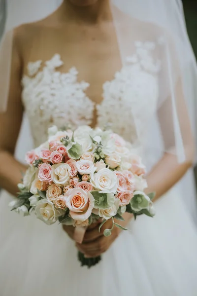 Porträt einer Hochzeitsbraut, die in einem weißen Hipster-Kleid mit Blumen in den Händen im Wald bei Sonnenuntergang posiert — Stockfoto