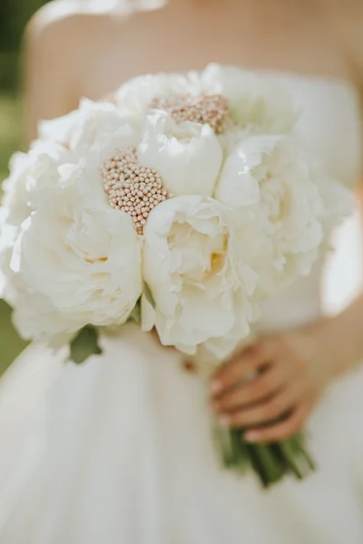 Ritratto di una sposa nuziale in posa in un abito bianco stile hipster con fiori tra le mani nella foresta al tramonto — Foto Stock