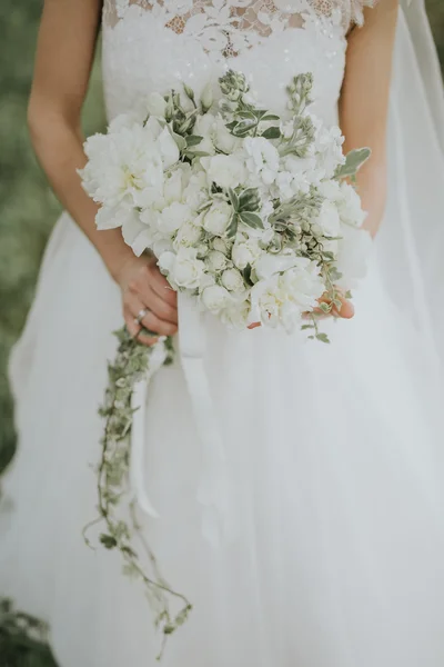 일몰에 숲에서 그녀의 손에 있는 꽃을 가진 백색 hipster 스타일 드레스에서 포즈 웨딩 신부 초상화 — 스톡 사진