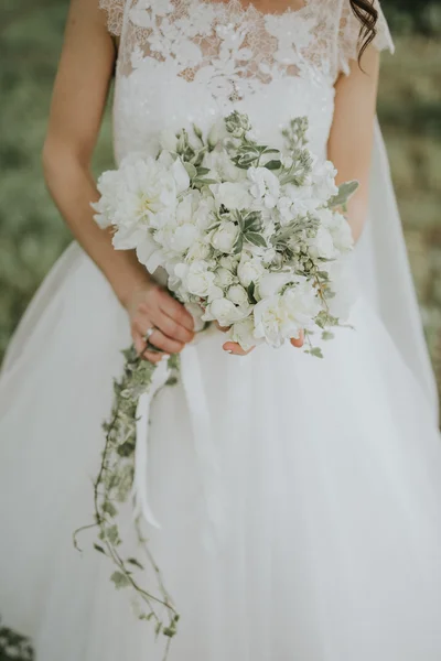 夕日の森で手に花を持つ白いヒップ スタイル ドレスでポーズをとって結婚式の花嫁の肖像画 — ストック写真